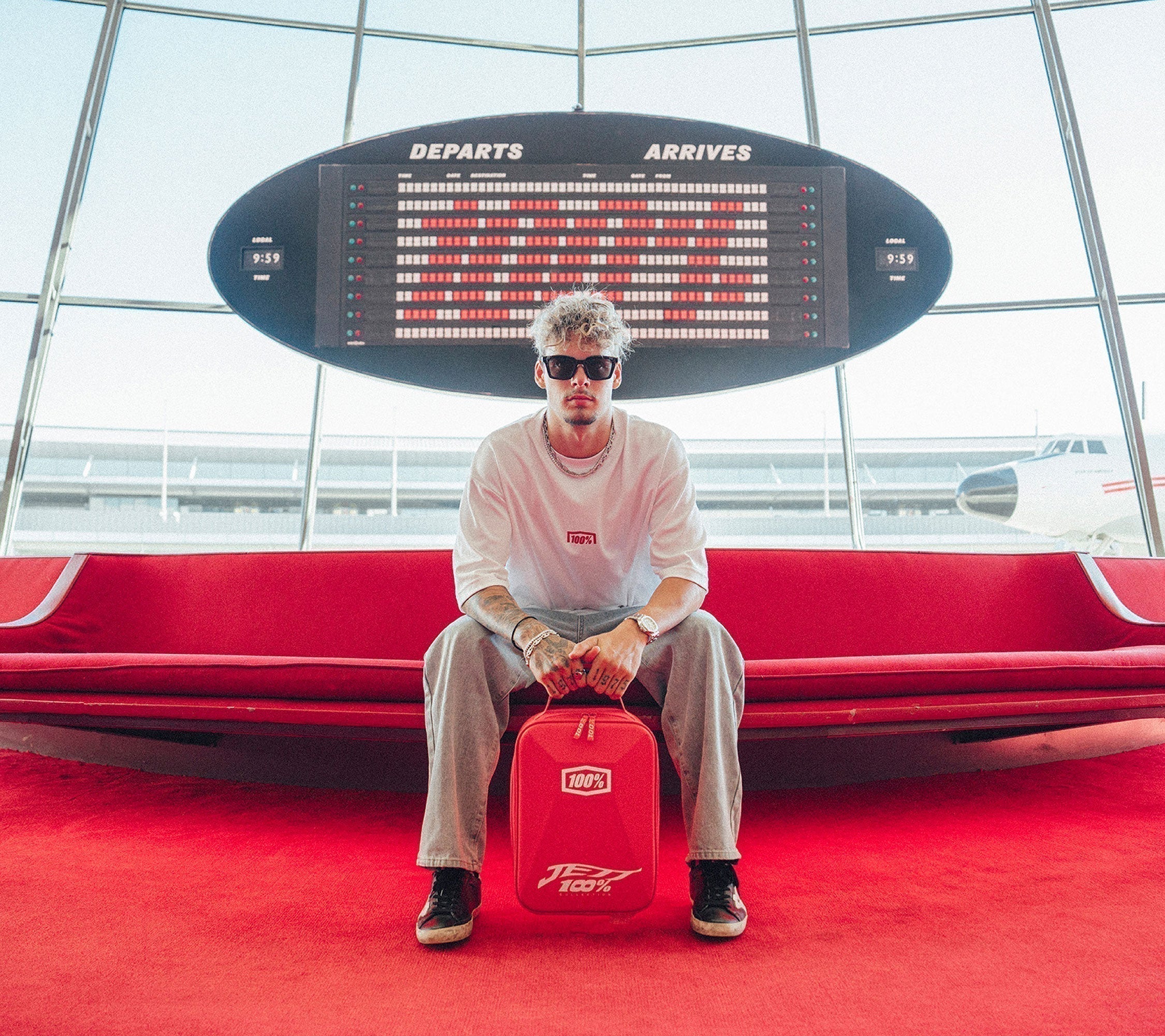 Jett Sitting at the airport holding the 100Percent® Limited Edition Armega JettPak Case