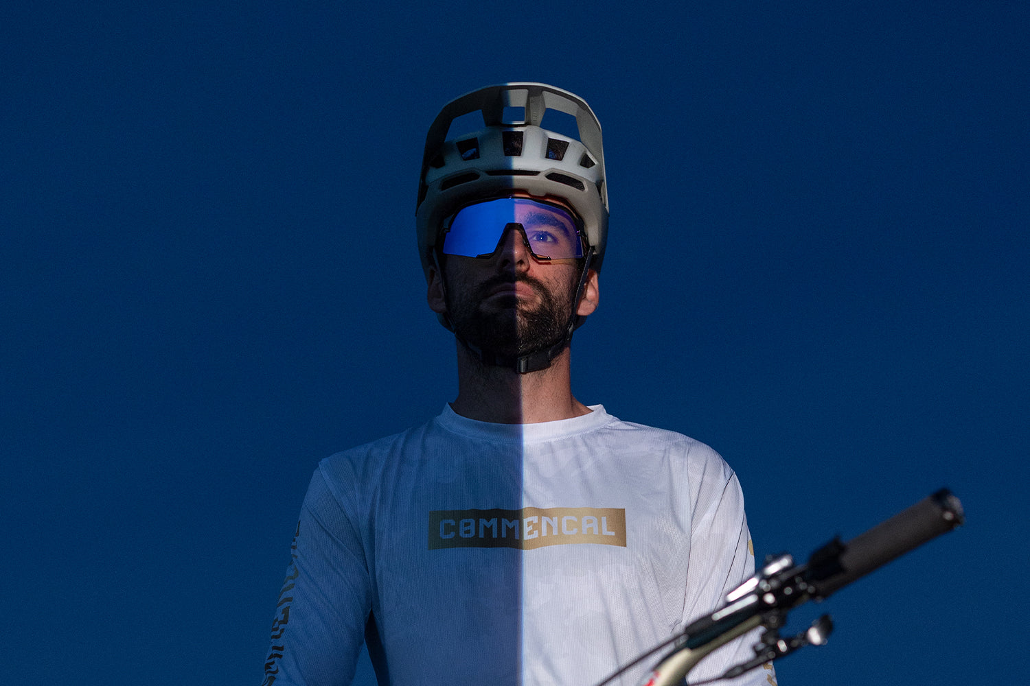 100Percent® Kilian Bron with the SLENDALE® Gloss Black Purple Mirror Photochromic Lens half dark, half light showing the Photochromic lens
