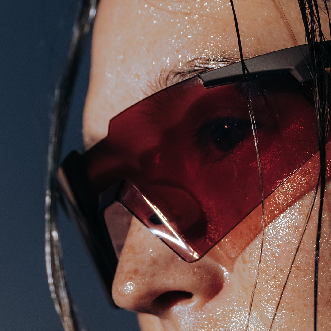 100Percent® A2 Running Sunglasses Red on a woman with a blue background.